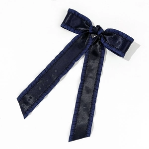 Detail of navy blue satin bow hair clip with ruffle edges and long elegant ribbons