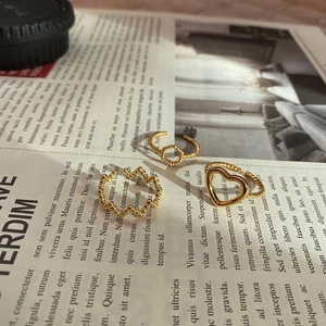 Detailed view of three vintage gold rings with heart and wave designs on retro paper