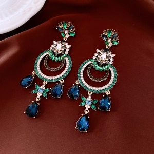 Vue macro de boucles d'oreilles vintage avec cristaux vert émeraude et gemmes bleues en goutte