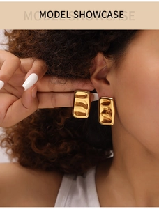 Detail shot of golden rectangular earrings with wave texture on model showcase