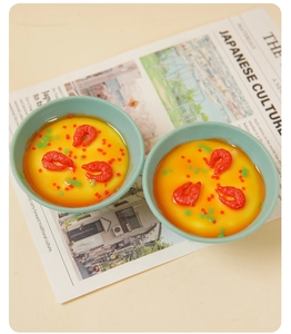 Vista superior de dos mini huevos al vapor de juguete con gambas sobre una revista