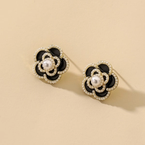 Detailed close-up of retro black enamel flower stud earrings with elegant pearl accents