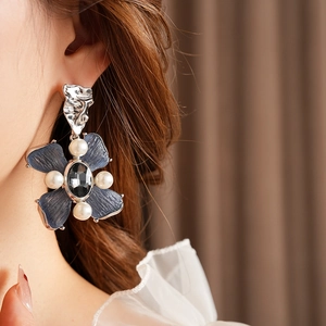 Detail of vintage blue flower earring with central black stone and pearls on model