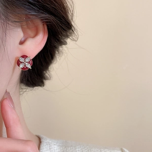 Close-up of red enamel flower earrings with diamond accents worn by a model