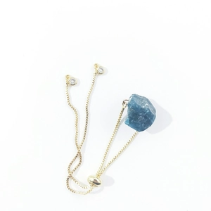 Detail of blue natural crystal stone set on a golden adjustable slider chain bracelet