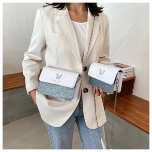 Close-up of stylish chain flap bag with silver butterfly and white leather texture