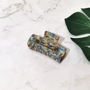 Detailed view of large marble texture acetate hair claw clip with blue and brown patterns