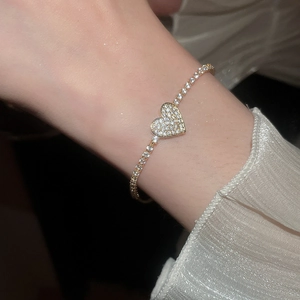 Detail of a sparkling heart tennis bracelet with gold finish and brilliant zircon stones
