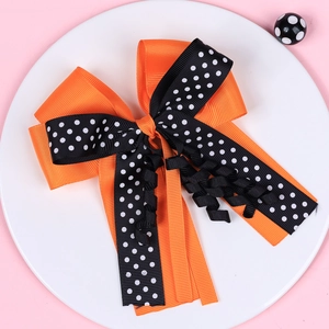 Detail of Halloween bow hair clip featuring orange and polka dot ribbons with long tails