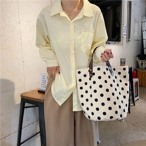 Detail of a retro polka dot canvas bucket bag paired with a casual yellow shirt