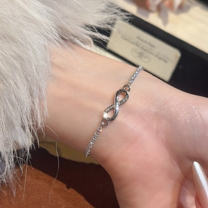 Close-up of infinity symbol bracelet with white zircon inlay on silver chain