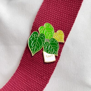 Cartoon potted plant enamel brooch with green leaves and golden trim on fabric