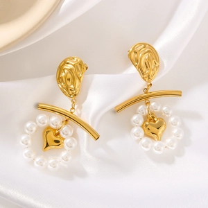 Vintage gold heart and pearl earrings on white silk fabric in a soft lighting scene