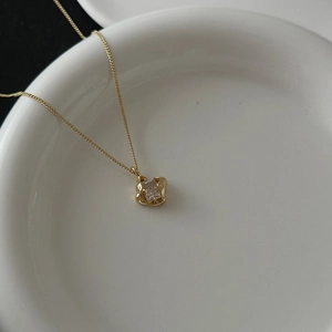 Detailed close-up of 18k gold plated necklace with a square zircon pendant on white tray