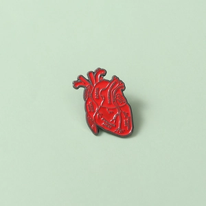 Dettaglio della spilla in smalto a cuore anatomico rosso con etichette mediche come Aorta