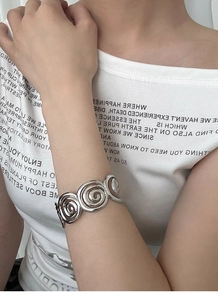 Macro view of silver geometric spiral disc bracelet with vintage industrial metallic texture
