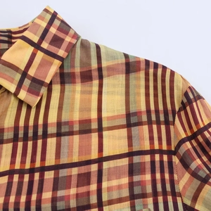Détail de chemise à carreaux multicolore montrant la texture lin et les coutures
