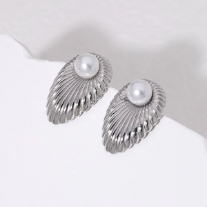 Elegant silver shell stud earrings with white pearls on a minimalist white stone pedestal