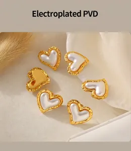 Macro detail of PVD 18K gold plated heart stud earrings with white pearl inlay