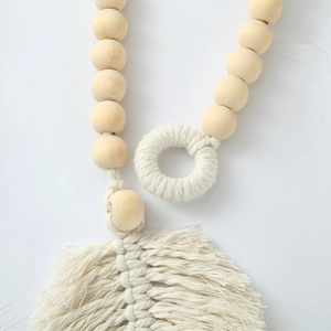 Close-up of bohemian cotton rope curtain tieback with wooden beads and tassel leaf