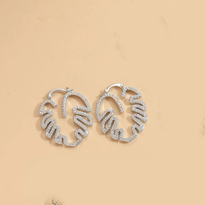 Close-up of silver monstera leaf earrings with shimmering white cubic zirconia stones