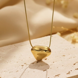 Macro shot of polished gold irregular heart pendant on a fine snake chain necklace