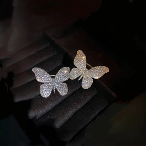 Elegant gold and silver butterfly brooches with sparkling crystals on dark velvet background