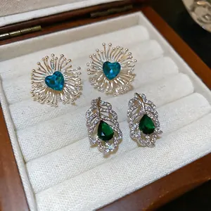 Boucles d'oreilles en argent avec cœur bleu et cristaux verts dans un écrin à bijoux
