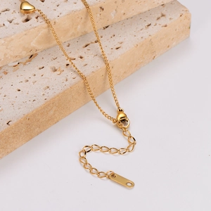 Elegant gold stainless steel heart necklace displayed on minimalist stone blocks