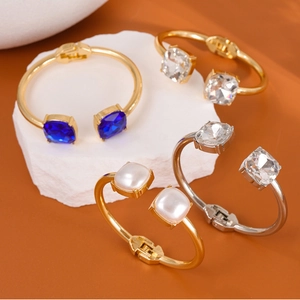 Detail view of square gemstone and pearl inlay cuff bangles on stone displays