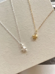 Detail of gold and silver brushed star necklaces featuring a sparkling zircon stone inlay