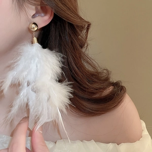 Elegant white feather tassel earrings with gold sphere accents worn by a female model