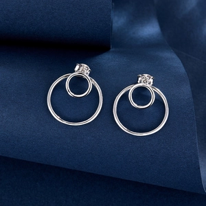 Detail of silver double circle earrings on a dark blue textured background