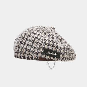 Close-up of houndstooth beret featuring LOVES metal letters and silver chain detail