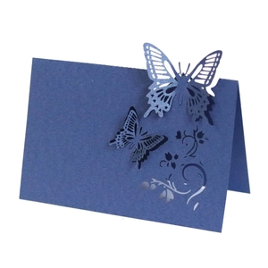 Macro detail of laser-cut butterfly design on navy blue paper place cards for wedding