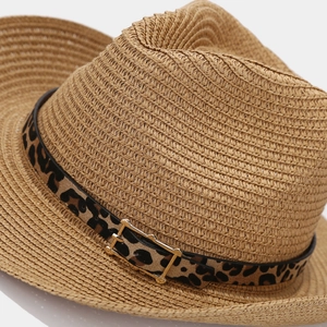 Detailed view of woven straw Panama hat with leopard print band and gold buckle