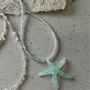 Detailed close-up of blue starfish pendant with translucent handmade beaded necklace