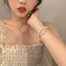 Detail of silver planet moon necklace and bracelet with white pearls on a model
