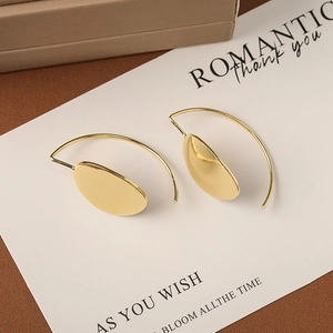 Macro view of gold minimalist oval hoop earrings on a romantic white greeting card