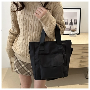 Detail showing high-quality nylon tote bag with functional front flap pocket and sturdy handles