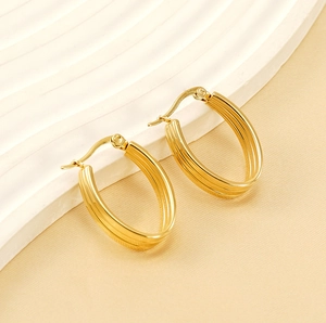 Détail de boucles d'oreilles dorées en U avec texture nervurée triple sur support blanc