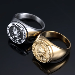 Detail of gold and silver praying hands signet rings with rope edge on black background