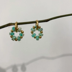 Macro detail of 18K gold earrings featuring natural turquoise stones on branch display