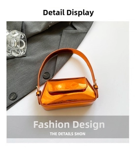 Detail of bright orange metallic mini baguette bag with shiny texture and top handle