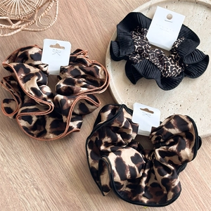 Detailed macro view of layered leopard print hair scrunchies with pleated fabric texture