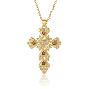 Macro shot of gold cross pendant with red gemstones and sparkling white zirconia