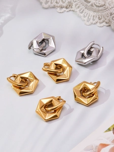 Detailed macro view of geometric hexagonal earrings in polished gold and silver finishes