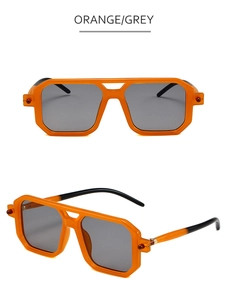 Close-up of orange rectangular sunglasses with metal rivets and dark grey lenses