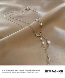 Detail of silver moon and star pendant necklace with pearls on champagne silk fabric