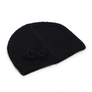 Detail of black knit beanie featuring vertical ribbed texture and a soft side flower